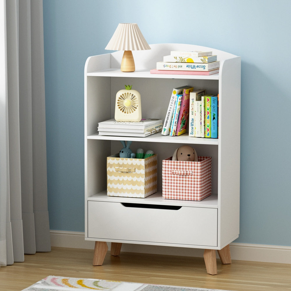 White bookshelf with books, toys, and decorative items against a blue wall.