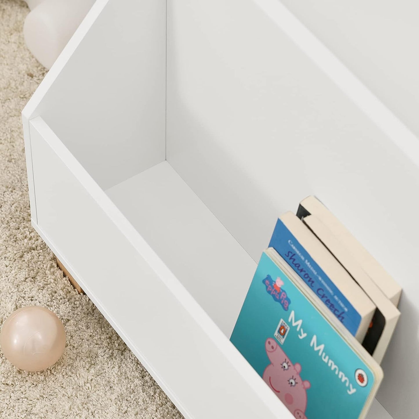 Children's books in a white storage box on a light-colored floor.