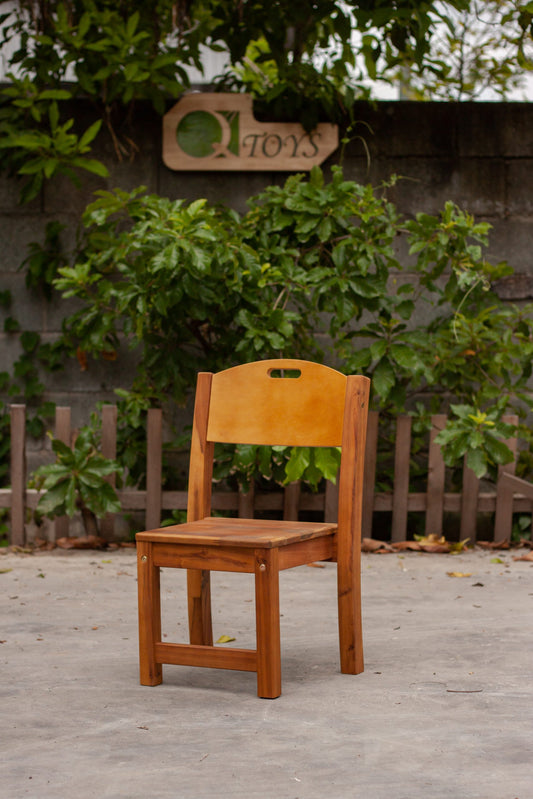 Wooden chair on a wooden deck with greenery and a sign in the background